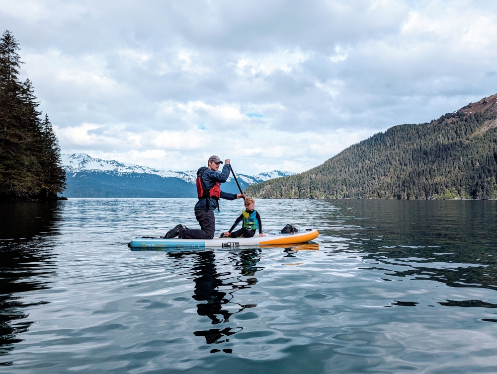 Father and young son Paddle Boarding wearing wet suits and life jackets